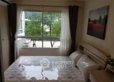 Cozy bedroom with large window and scenic view, perfect for relaxation.