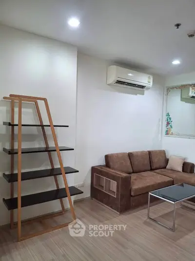 Modern living room with sleek shelving and comfortable sofa, featuring minimalist design and air conditioning.
