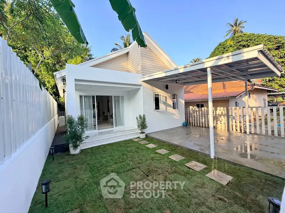 Charming modern white house with lush garden and spacious carport, perfect for serene living.