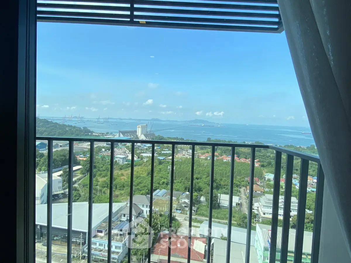 Stunning high-rise balcony view overlooking lush greenery and distant ocean horizon.