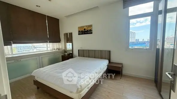 Spacious bedroom with large windows offering city views and modern furnishings.