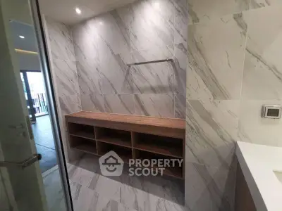 Modern bathroom with sleek marble tiles and wooden shelving unit