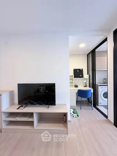 Modern living room with TV and study area featuring a washing machine, ideal for urban living.
