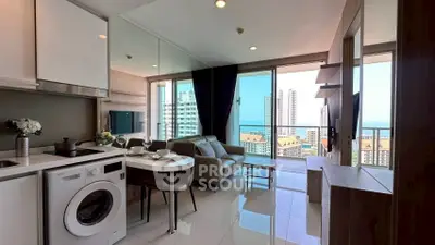 Modern open-plan living room with stunning city and sea views, featuring sleek kitchen and cozy seating area.