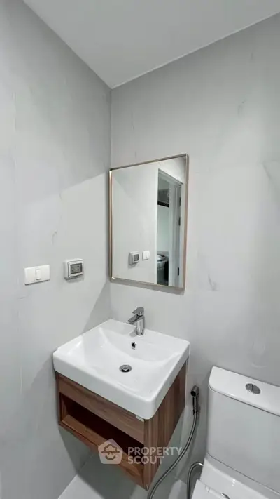 Modern bathroom with sleek sink and mirror, featuring minimalist design and neutral tones.