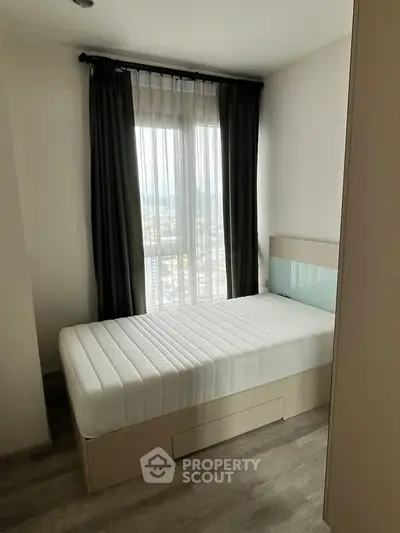 Cozy bedroom with single bed and large window offering natural light and city view.