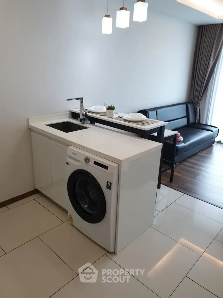 Modern open-plan living room with integrated laundry area and sleek furnishings.