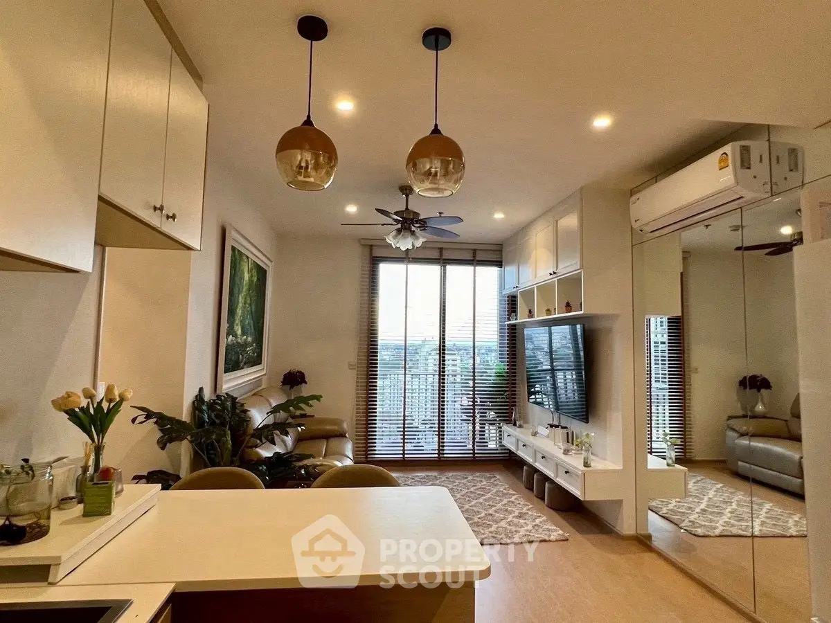 Modern living room with open kitchen, stylish decor, and large windows offering a scenic view.