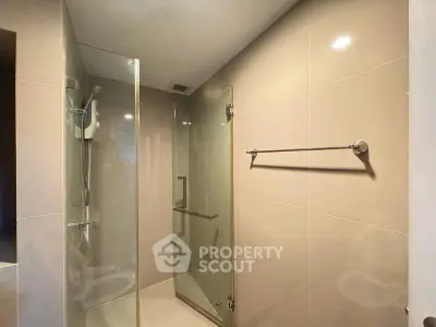 Modern bathroom with glass shower enclosure and sleek tile design.