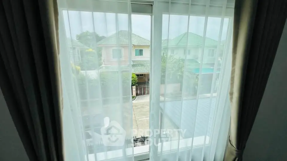 Charming window view of suburban homes with lush greenery and cozy neighborhood ambiance.