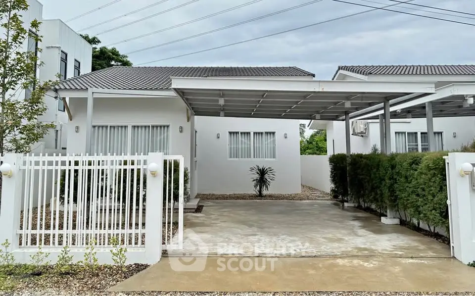 Charming single-story white house with carport and gated driveway in a serene neighborhood.