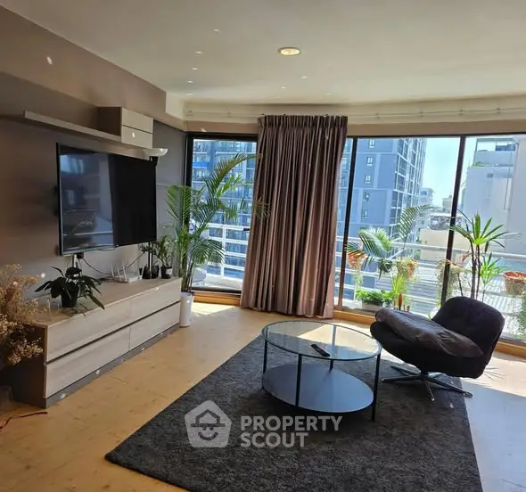 Spacious living room with large windows and modern decor in urban apartment.