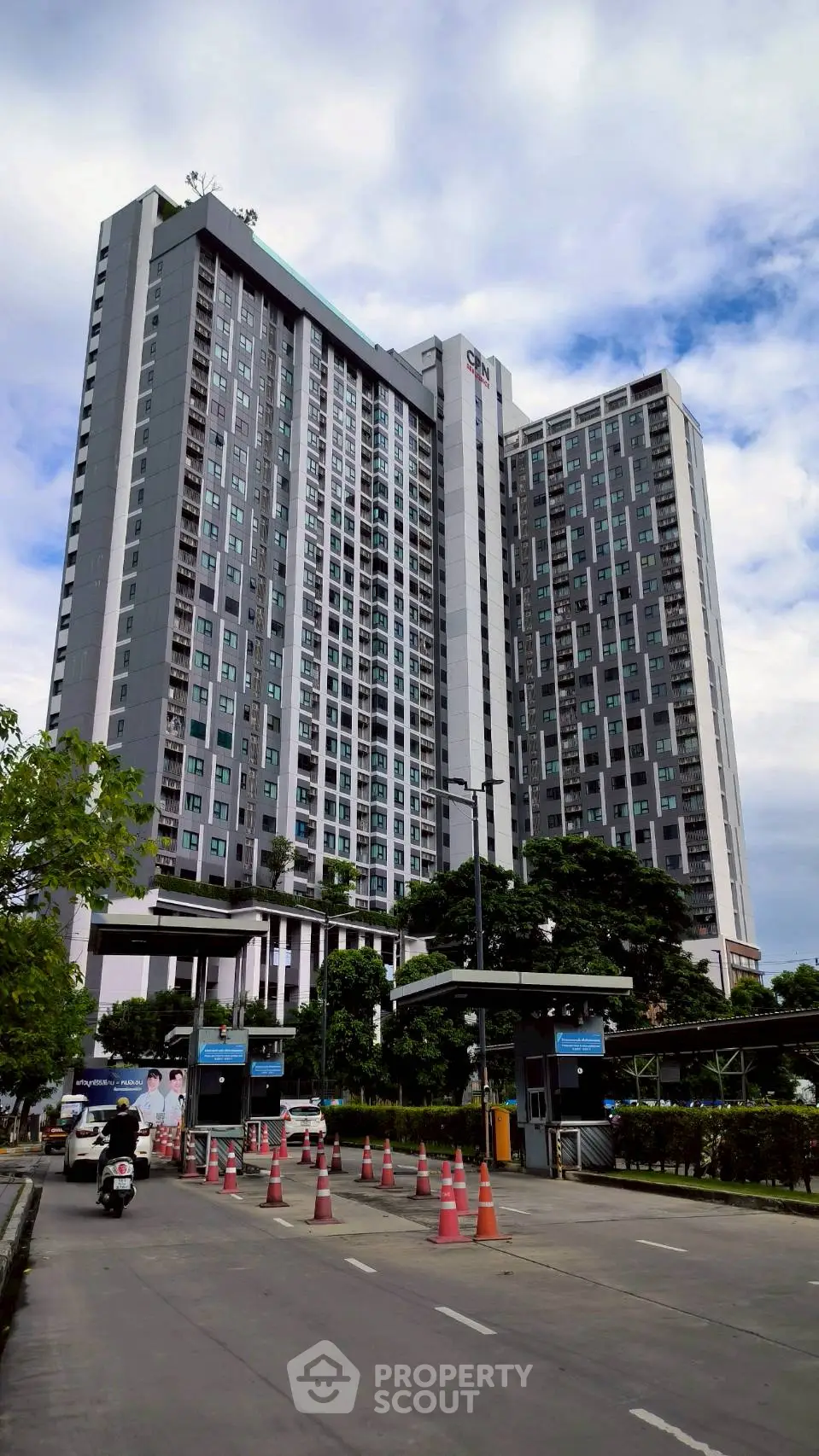 Modern high-rise residential building with lush greenery and secure entrance
