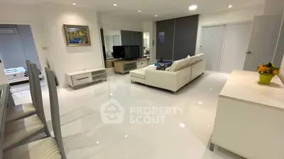 Spacious modern living room with sleek white furniture and glossy floors, perfect for stylish urban living.