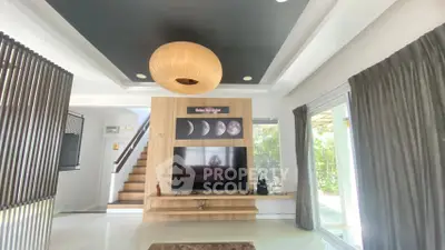 Spacious modern living room with stylish ceiling light and large TV, featuring a staircase and sliding glass doors.