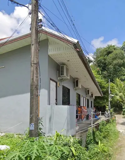 Charming residential building with lush greenery and modern air conditioning units.