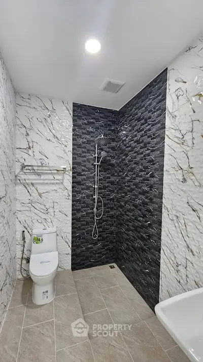 Modern bathroom with sleek black and white tile design and contemporary fixtures.