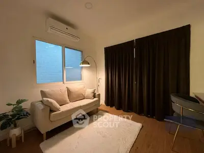 Cozy living room with sofa, floor lamp, and air conditioning unit.