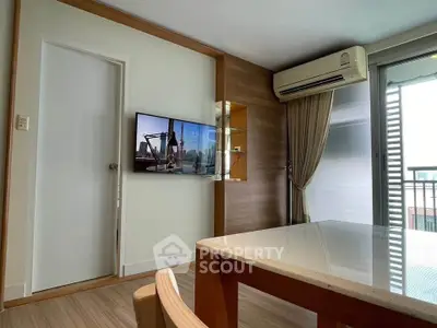 Modern living room with air conditioning and balcony access, featuring sleek furniture and a wall-mounted TV.