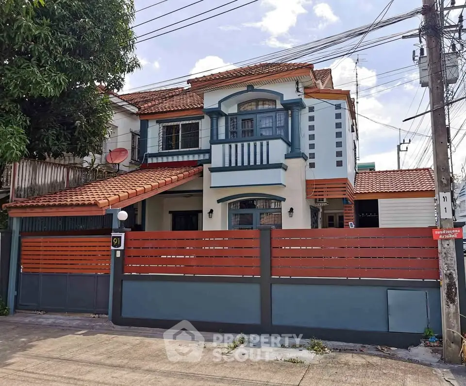 Charming two-story house with red-tiled roof and modern facade in a suburban neighborhood.