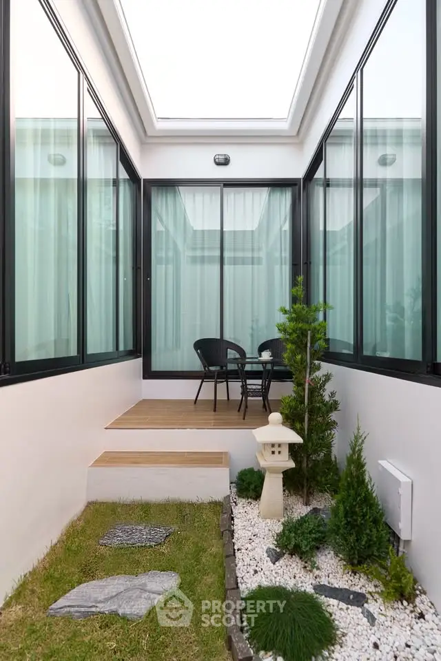 Charming small garden with modern glass enclosure and minimalist decor.