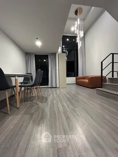 Modern living room with sleek flooring and stylish furniture, featuring a cozy seating area and elegant lighting.