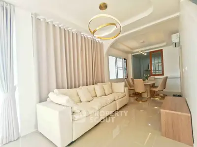 Elegant living room with modern decor and dining area, featuring plush sofa and stylish lighting.