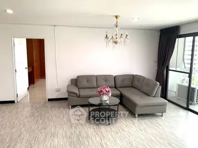 Spacious living room with modern gray sofa and elegant chandelier in a bright apartment.