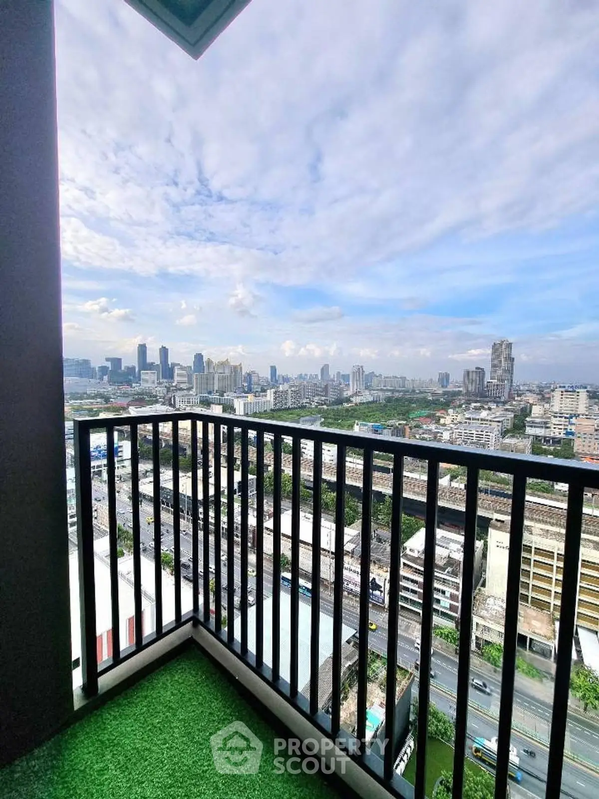 Stunning cityscape view from a high-rise balcony with lush green flooring.