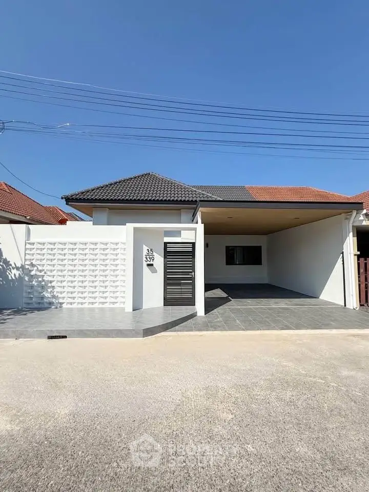 Modern single-story house with carport and minimalist design under clear blue sky.