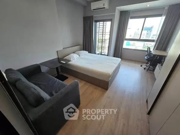 Modern bedroom with city view, featuring a cozy bed and stylish decor.