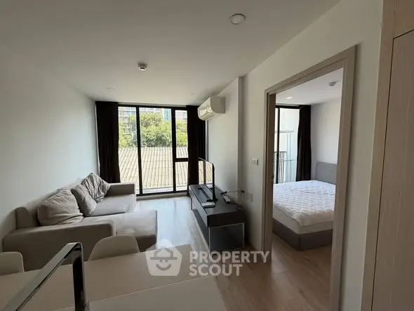 Modern apartment interior with living room and bedroom, featuring large windows and stylish furnishings.