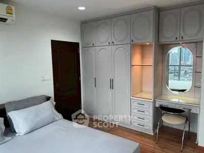 Spacious bedroom with built-in wardrobe and city view from window.