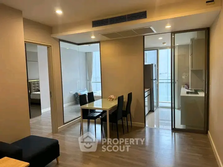 Modern apartment interior with open layout dining area and kitchen, featuring sleek design and natural lighting.