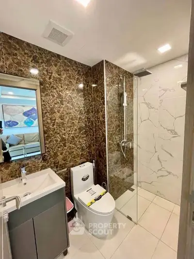 Modern bathroom with marble walls and glass shower enclosure