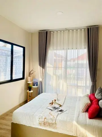 Bright and cozy bedroom with large window and elegant curtains, perfect for relaxation.