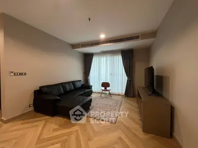 Modern living room with sleek black sofa and large TV, featuring elegant herringbone flooring.