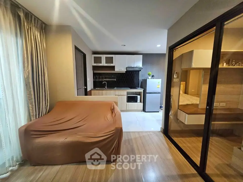 Modern studio apartment with cozy living area and compact kitchen featuring sleek appliances.
