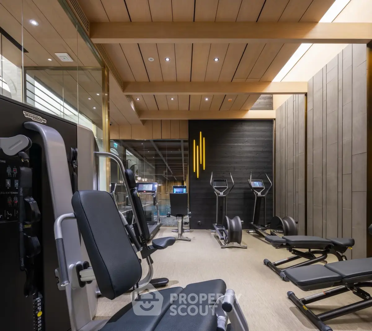 Luxurious modern gym with state-of-the-art equipment and stylish wooden ceiling design.