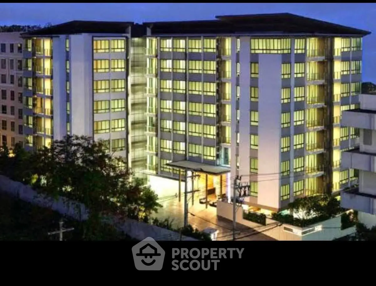 Modern apartment building with illuminated windows and sleek design at dusk.