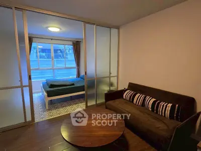 Cozy studio apartment with sliding glass doors separating bedroom and living area, featuring modern decor.