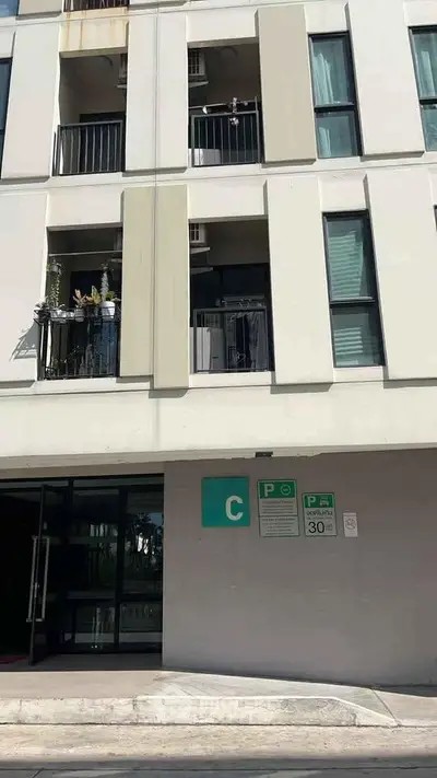 Modern apartment building exterior with parking sign and balconies.