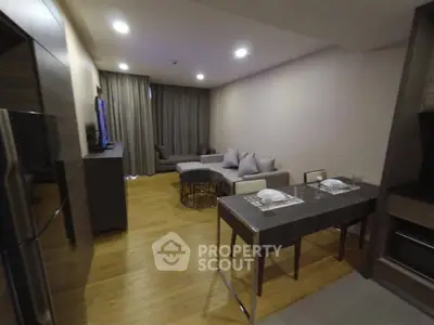 Modern living room with sleek furniture and dining area in open layout apartment.