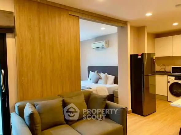 Modern open-plan living room with kitchen and bedroom, featuring sleek appliances and cozy furnishings.