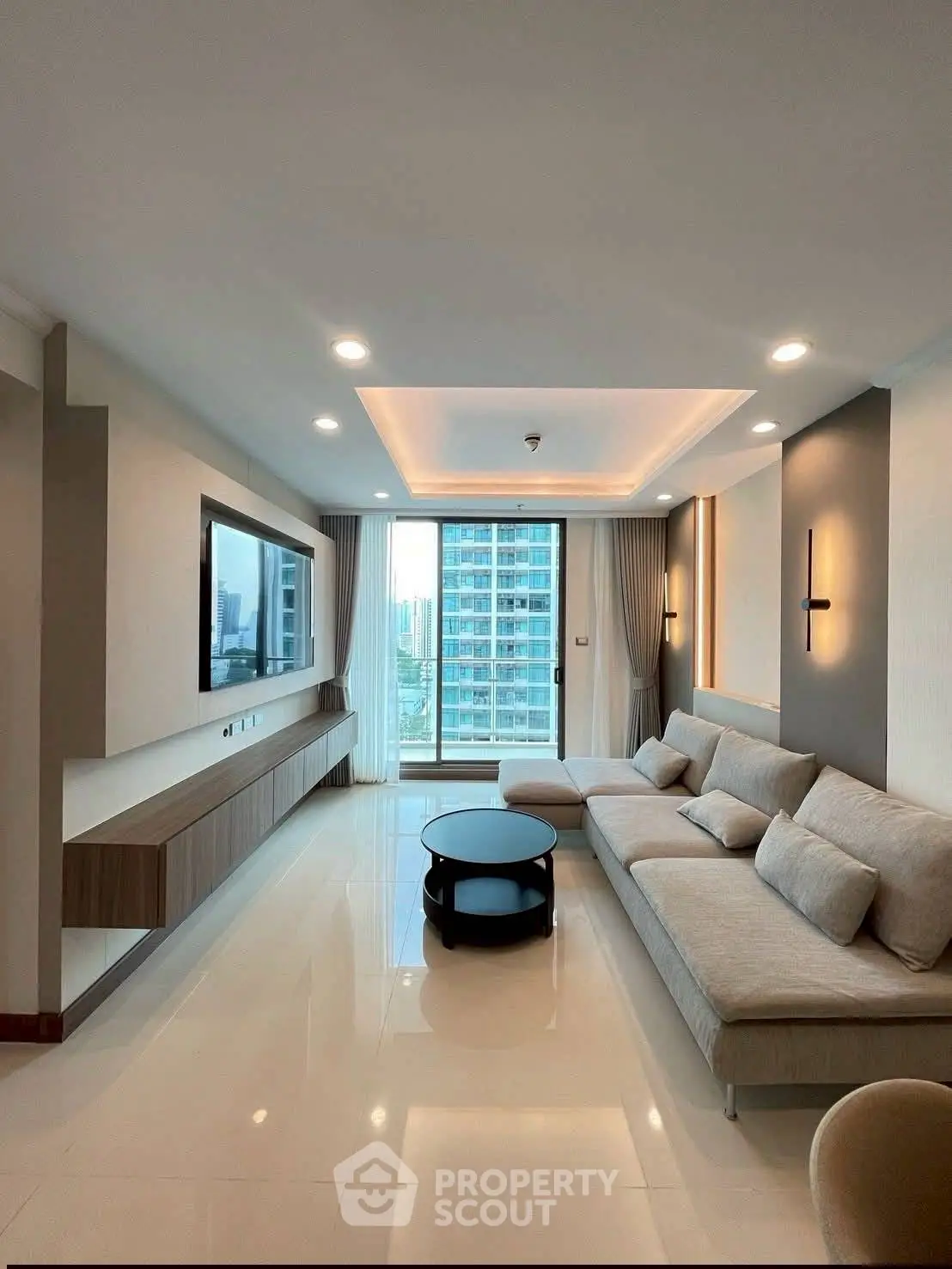 Modern living room with sleek design and city view, featuring a spacious sofa and large TV.
