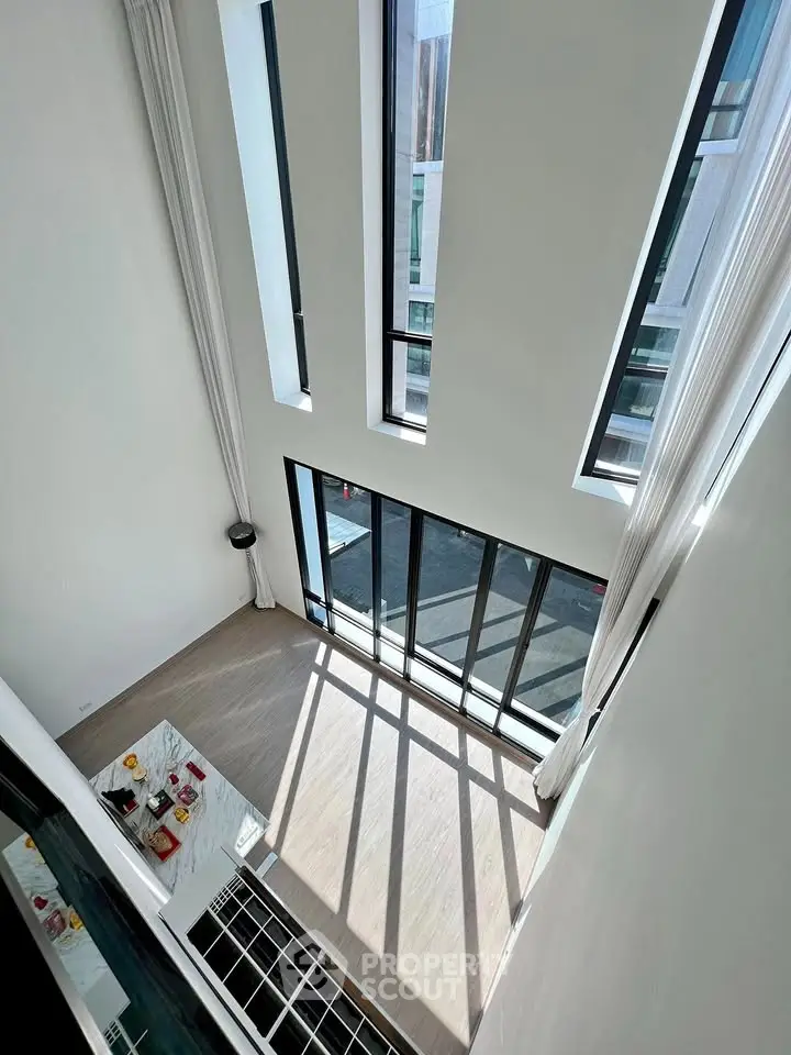 Stunning high-ceiling living room with floor-to-ceiling windows and abundant natural light.