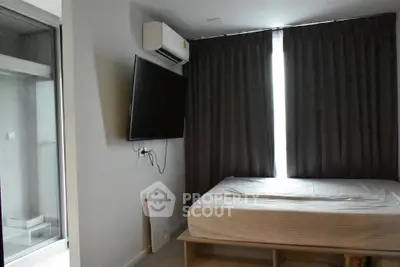Modern bedroom with wall-mounted TV and air conditioning, featuring sleek design and natural light.