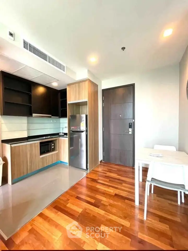 Modern kitchen with wooden flooring and sleek appliances in a bright apartment