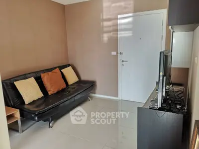 Cozy living room with modern black sofa and TV setup, perfect for relaxation.