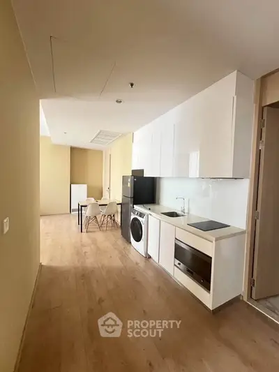 Modern kitchen with sleek appliances and dining area in open layout apartment.